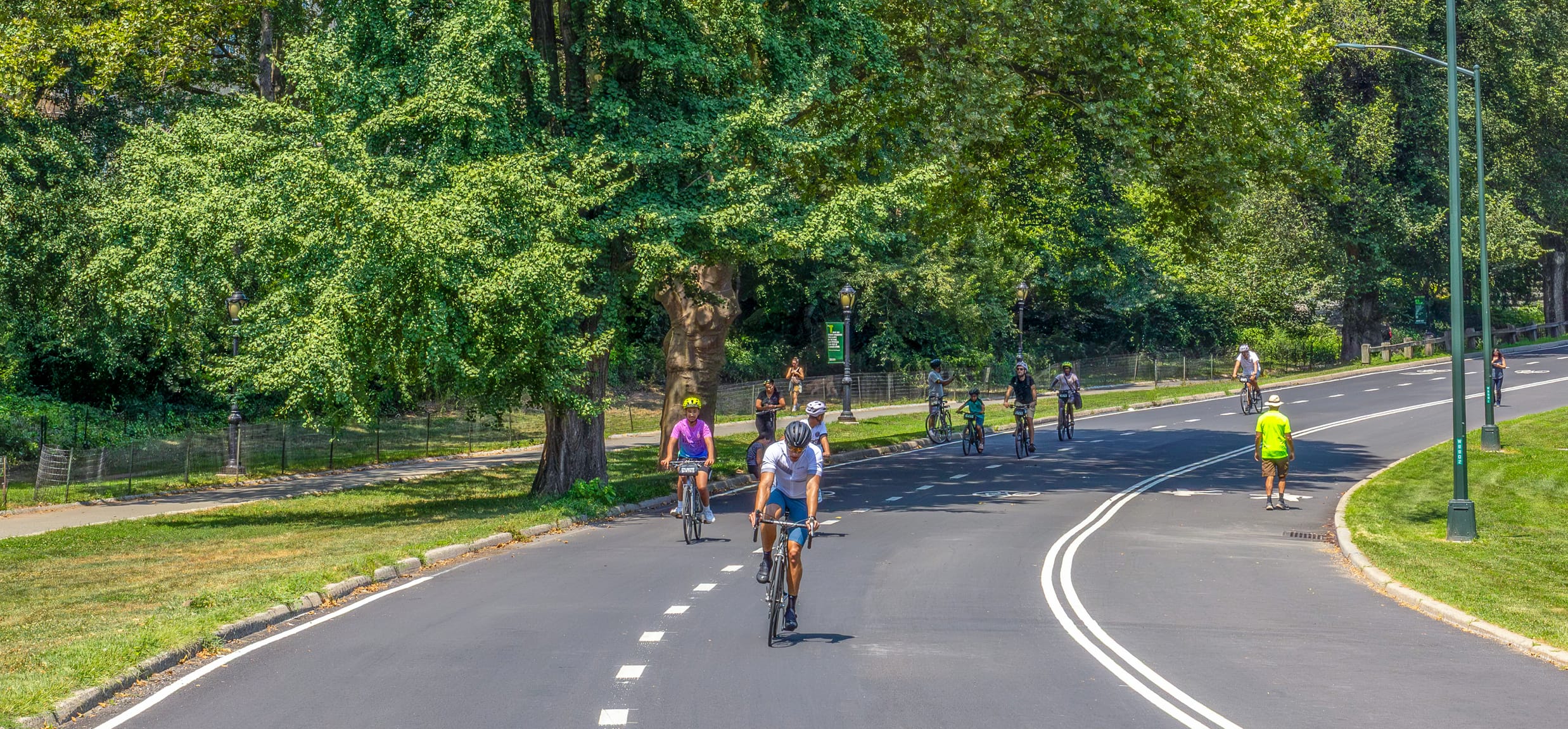 Person walking on the pedestrian inner lane and bicycle rider cycling on the middle and outer lanes of Central Park drives