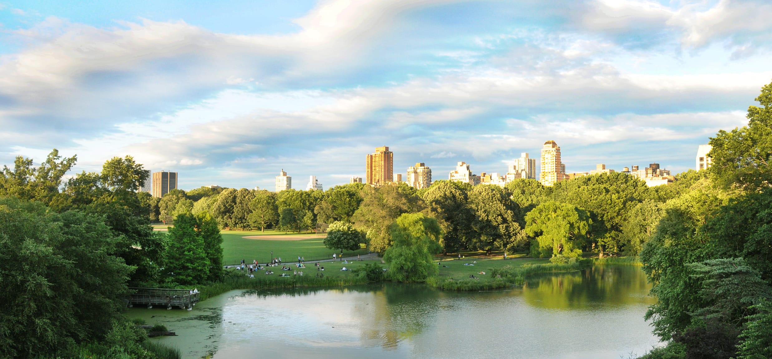 Tall buildings against a cloudy sky with the lake in the foreground